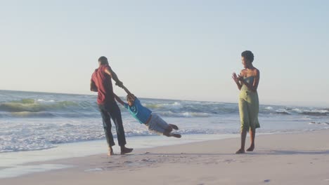 Video-Einer-Glücklichen-Afroamerikanischen-Familie,-Die-Sich-Bei-Sonnenuntergang-Am-Strand-Amüsiert