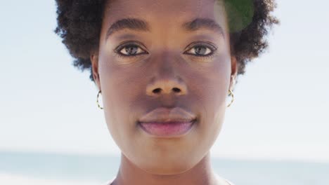 Video-Des-Gesichts-Einer-Glücklichen-Afroamerikanischen-Frau,-Die-Am-Strand-In-Die-Kamera-Blickt