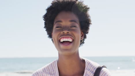 Video-Des-Gesichts-Einer-Glücklichen-Afroamerikanischen-Frau,-Die-Am-Strand-In-Die-Kamera-Blickt