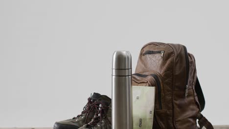 Camping-equipment-with-rucksack,-thermos-and-boots-and-copy-space-on-white-background