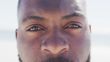 Video-Des-Gesichts-Eines-Afroamerikanischen-Mannes,-Der-Am-Strand-In-Die-Kamera-Blickt