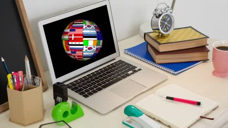 Animation-of-globe-with-flags-on-laptop-screen-on-desk