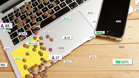 Animation-of-social-media-icons-and-face-emojis-against-laptop-and-smartphone-on-wooden-table
