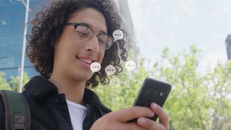 Animation-of-message-icons-over-biracial-young-man-using-cellphone-in-outdoors