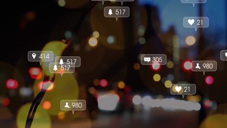 Animation-of-social-media-icons-falling-against-night-city-traffic