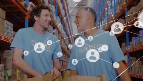 Animation-of-network-of-icons-over-two-caucasian-male-volunteers-high-fiving-each-other-at-warehouse