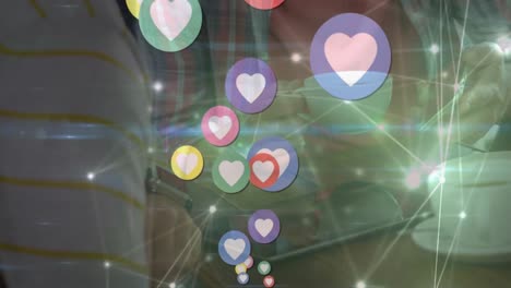 Animation-of-heart-icons-and-network-of-connections-over-biracial-man-using-a-smartphone-at-a-cafe