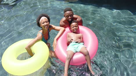 Portrait-of-happy-african-american-parents-and-son-playing-at-pool,-in-slow-motion
