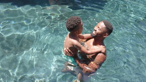 Glücklicher-Afroamerikanischer-Vater-Und-Sohn-Spielen-Am-Pool,-In-Zeitlupe
