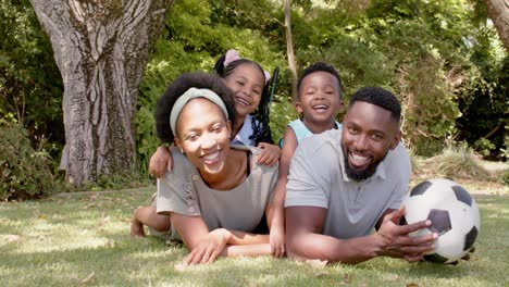 Portrait-of-happy-african-american-family-with-football-in-garden,-in-slow-motion