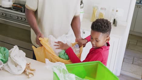 Glücklicher-Afroamerikanischer-Vater-Und-Sohn,-Die-In-Zeitlupe-Müll-In-Der-Küche-Sortieren