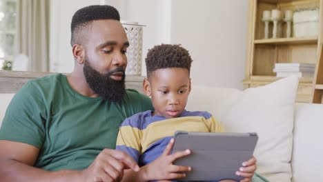 Feliz-Padre-E-Hijo-Afroamericanos-Sentados-En-El-Sofá,-Usando-Una-Tableta,-En-Cámara-Lenta