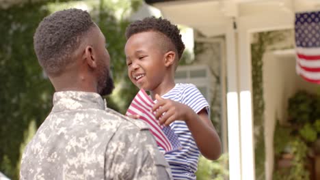 Feliz-Soldado-Afroamericano-Abrazando-A-Su-Hijo-Con-Bandera-Americana,-En-Cámara-Lenta