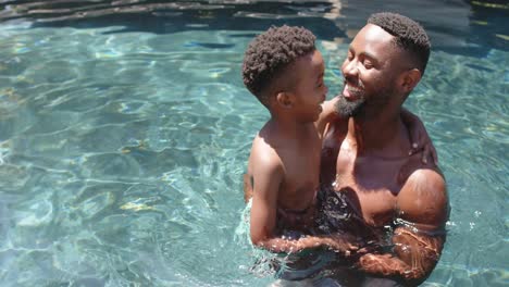 Glücklicher-Afroamerikanischer-Vater-Und-Sohn-Spielen-Am-Pool,-In-Zeitlupe