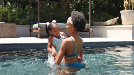 Happy-african-american-mother-and-daughter-playing-at-pool,-in-slow-motion