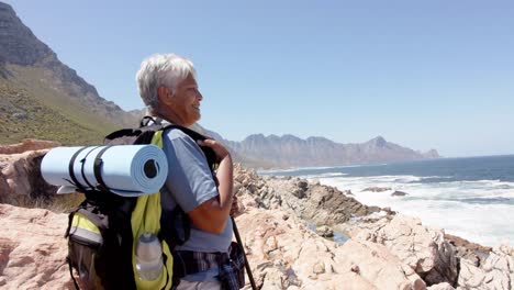Happy-senior-biracial-woman-in-mountains-resting-at-sea,-in-slow-motion