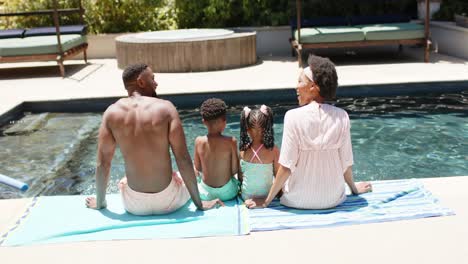 Happy-african-american-family-sitting-at-pool,-in-slow-motion