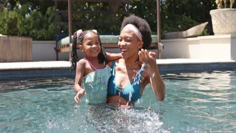 Porträt-Einer-Glücklichen-Afroamerikanischen-Mutter-Und-Tochter,-Die-In-Zeitlupe-Am-Pool-Spielt