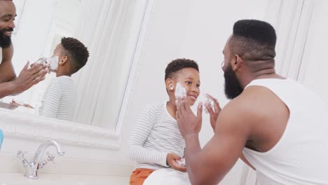 Glücklicher-Afroamerikanischer-Vater-Und-Sohn,-Der-Im-Badezimmer-Rasierschaum-Auf-Das-Gesicht-Aufträgt,-In-Zeitlupe