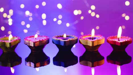 Nahaufnahme-Von-Lichtern-Und-Brennenden-Kerzen,-Die-Diwali-Auf-Violettem-Hintergrund-Feiern,-Mit-Kopierraum