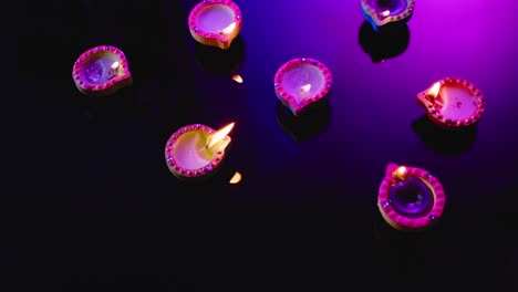 Close-up-of-burning-colourful-candles-celebrating-diwali-on-black-background