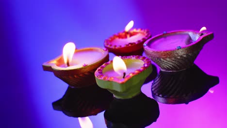 Close-up-of-burning-candles-celebrating-diwali-on-blue-background