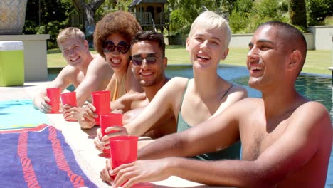 Portrait-of-happy-diverse-friends-drinking-drinks-at-pool-party-in-summer