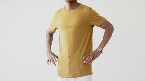 Midsection-of-african-american-man-wearing-yellow-t-shirt-with-copy-space-on-white-background