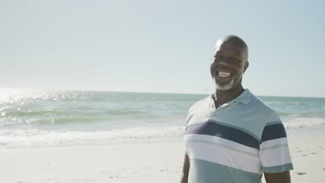 Portrait-of-happy-senior-african-american-man-smiling-at-beach,-in-slow-motion,-with-copy-space
