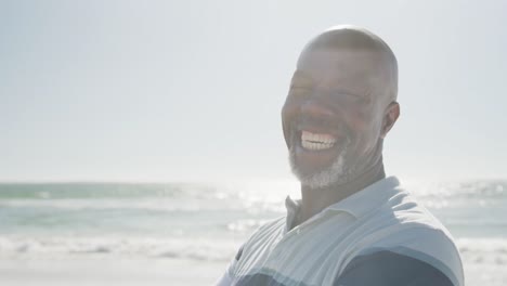 Portrait-of-happy-senior-african-american-man-smiling-at-beach,-in-slow-motion,-with-copy-space