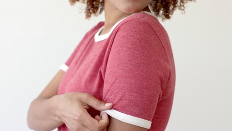 Midsection-of-african-american-woman-wearing-red-t-shirt-with-copy-space-on-white-background