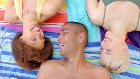 Portrait-of-happy-diverse-group-of-friends-lying-on-towels-in-summer