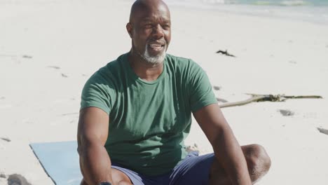Glücklicher-älterer-Afroamerikanischer-Mann,-Der-Yoga-Am-Strand-Macht,-In-Zeitlupe