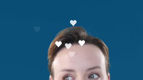 Animation-of-heart-shapes-flying-over-caucasian-young-woman-raising-eyebrows-over-blue-background