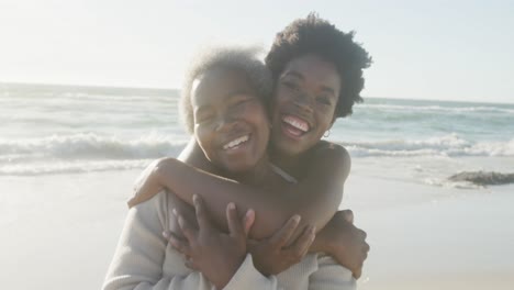 Portrait-of-senior-african-american-mother-and-adult-daughter-embracing-at-beach,-in-slow-motion