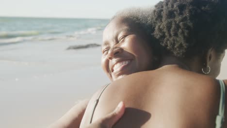 Glückliche-ältere-Afroamerikanische-Mutter-Und-Erwachsene-Tochter-Umarmen-Sich-Am-Strand,-In-Zeitlupe