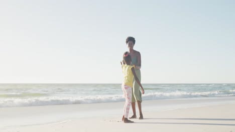Happy-african-american-mother-and-daughter-dancing-at-beach,-in-slow-motion