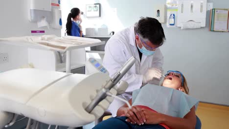 Dentista-Examinando-Los-Dientes-De-Un-Paciente-Bajo-Una-Luz-Brillante