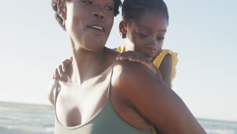 Happy-african-american-mother-and-daughter-embracing-at-beach,-in-slow-motion