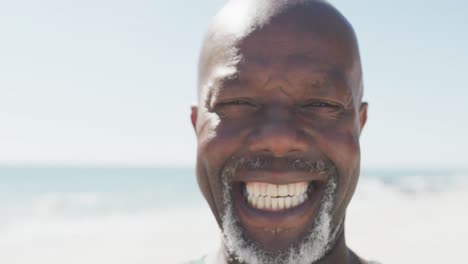 Portrait-of-happy-senior-african-american-man-smiling-at-beach-with-copy-space,-in-slow-motion