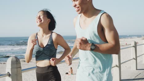 Happy-biracial-couple-running-on-promenade,-in-slow-motion