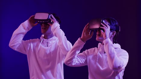 Asian-man-and-woman-using-vr-headsets-on-blue-background,-slow-motion