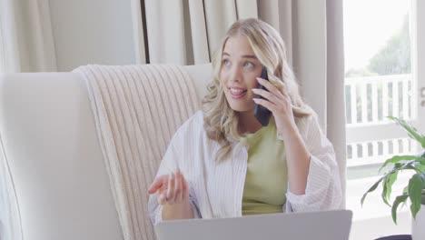 Happy-caucasian-plus-size-woman-talking-on-smartphone-and-using-laptop-in-slow-motion