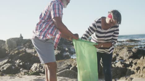 Senior-african-american-couple-cleaning-beach,-slow-motion