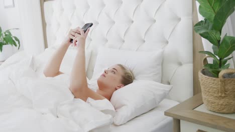 Glückliche-Kaukasische-Plus-Size-Frau,-Die-Ihr-Smartphone-Im-Bett-Benutzt