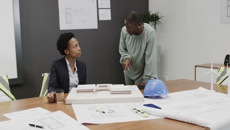 African-american-female-architects-discussing-blueprints-in-office,-in-slow-motion