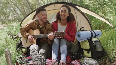 Happy-african-american-couple-camping,-playing-quitar-in-forest,-slow-motion