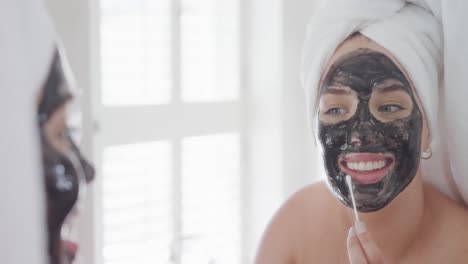 Happy-caucasian-plus-size-woman-with-towel-on-head-making-mask-in-slow-motion