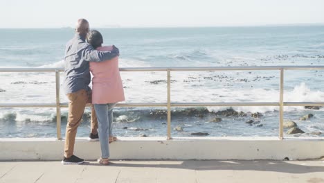 Happy-senior-african-american-couple-embracing-on-promenade-by-the-sea,-copy-space,-slow-motion