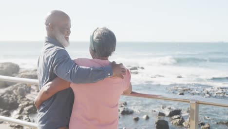 Glückliches-älteres-Afroamerikanisches-Paar,-Das-Sich-Auf-Der-Promenade-Am-Meer-Umarmt,-Zeitlupe